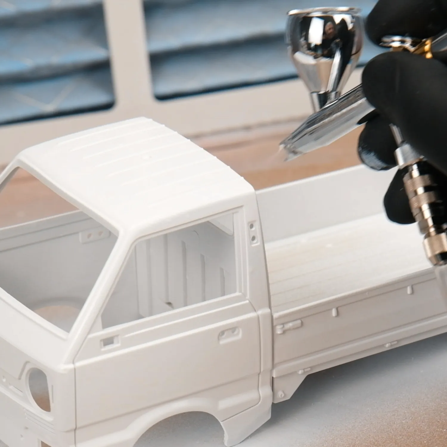 Weißes Modell aus Plastik wird mit der Airbrush grundiert